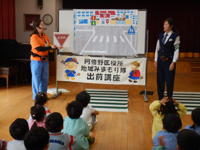 子どもたちに交通安全について教える区役所職員と警察官
