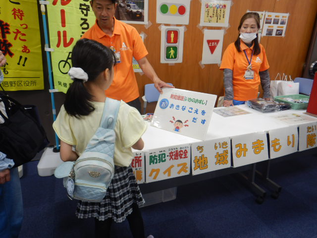 参加者に防犯標語「いかのおすし」のパネルで不審者にあった時の対応を説明する区役所職員