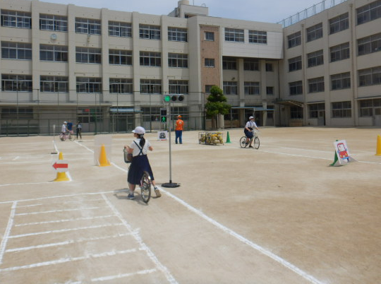 運動場で自転車の安全な乗り方を練習する児童