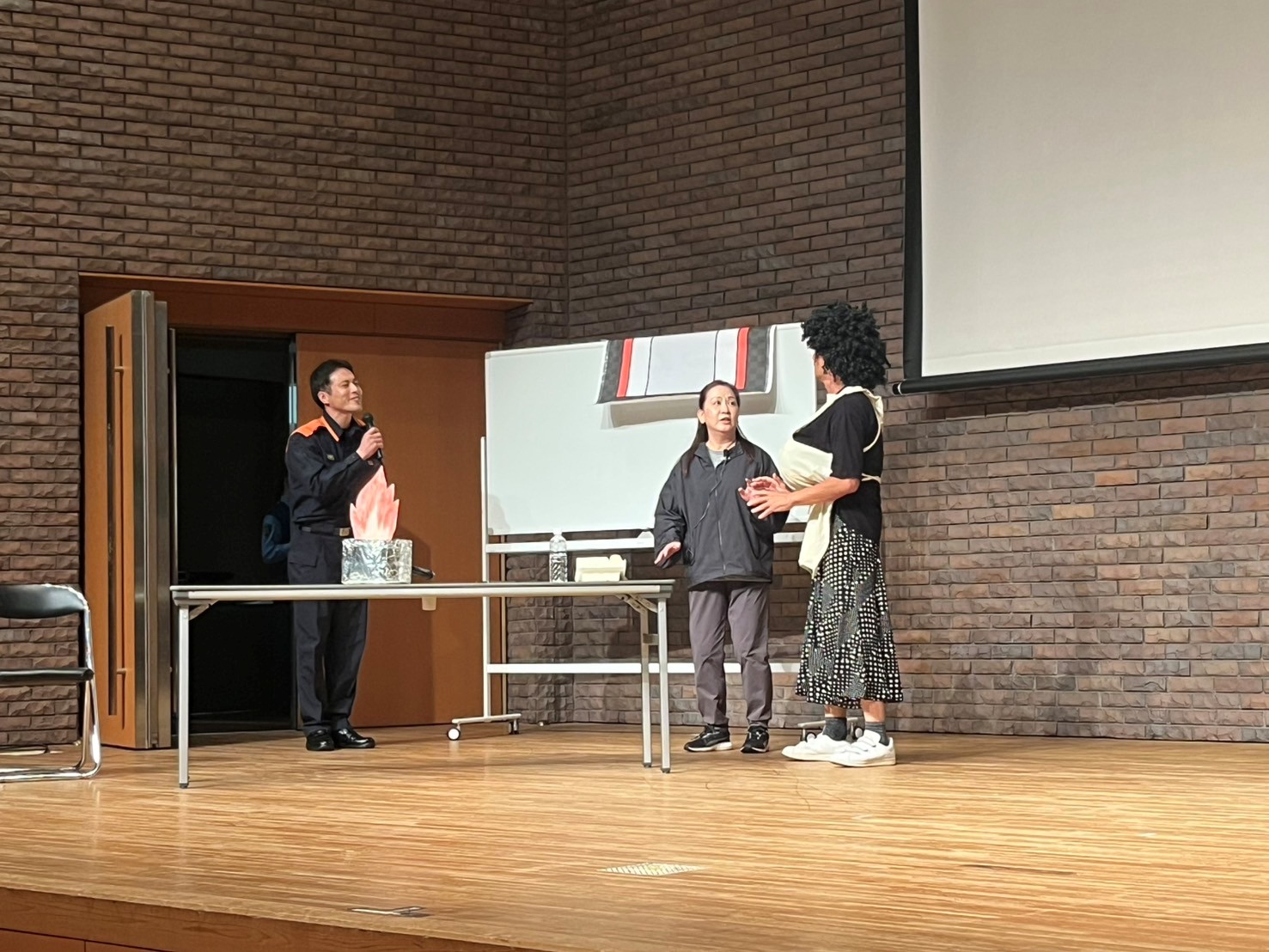 寸劇で天ぷら火災の対応を消防署員から説明を受ける演者