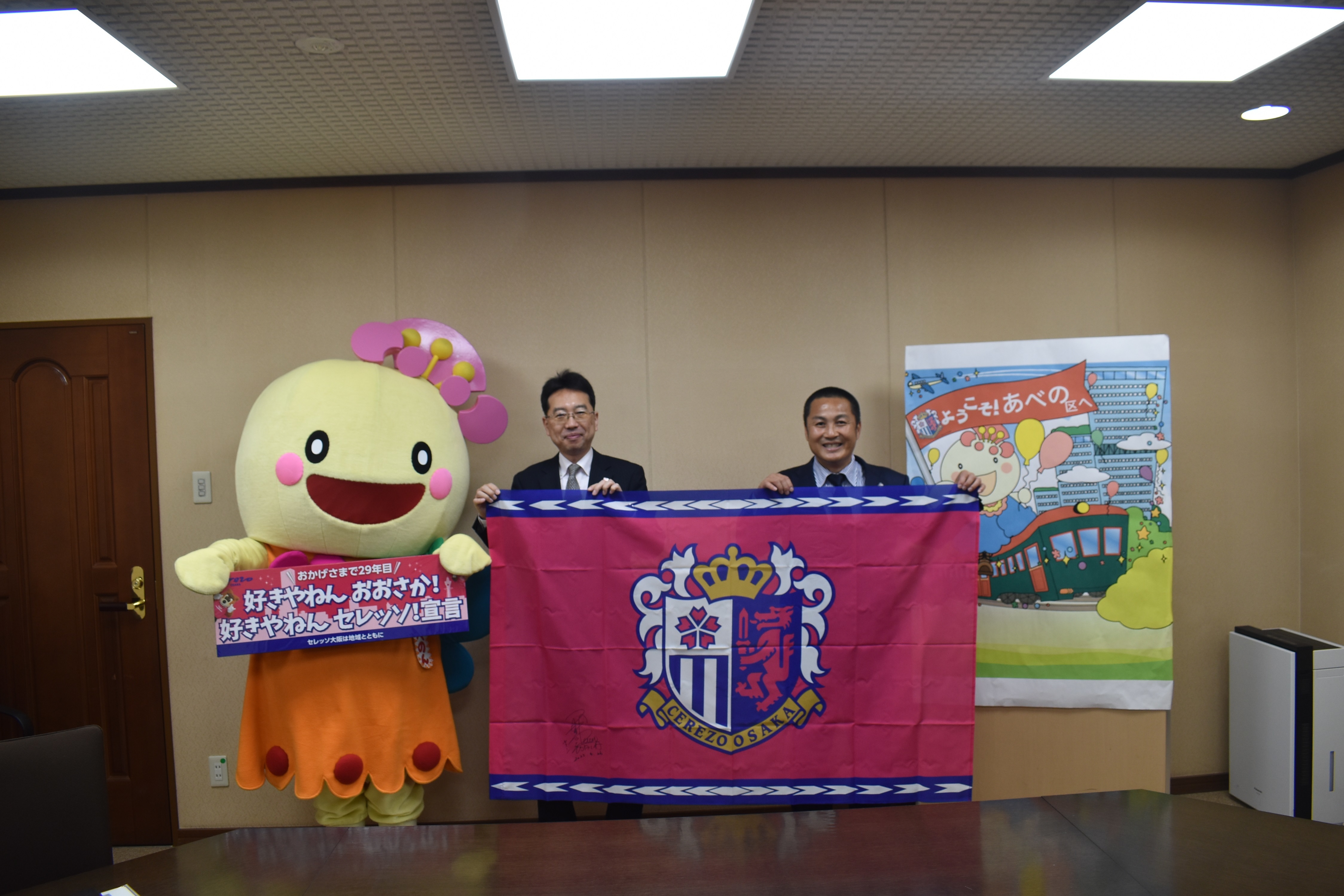 左からあべのん、森島社長、山田区長がセレッソの旗を持っている。