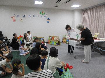たくさんの子どもたちが座って絵本に見入っている写真