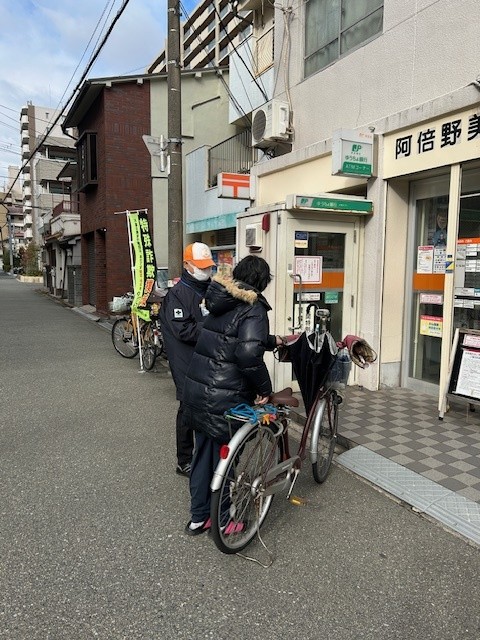 郵便局利用者に啓発物品を配付して注意喚起する区役所職員