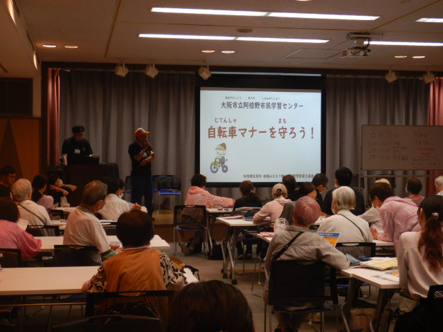 日本語読み書き教室の参加者に自転車マナーを呼びかける区役所職員