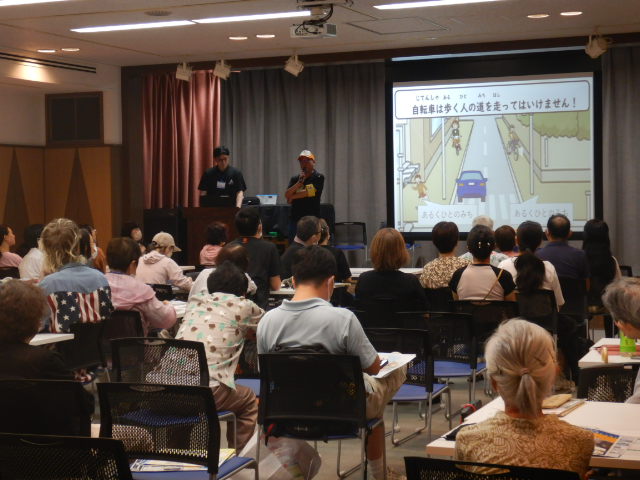 画像をスクリーンに映写し自転車のルールやマナーについて説明する区役所職員