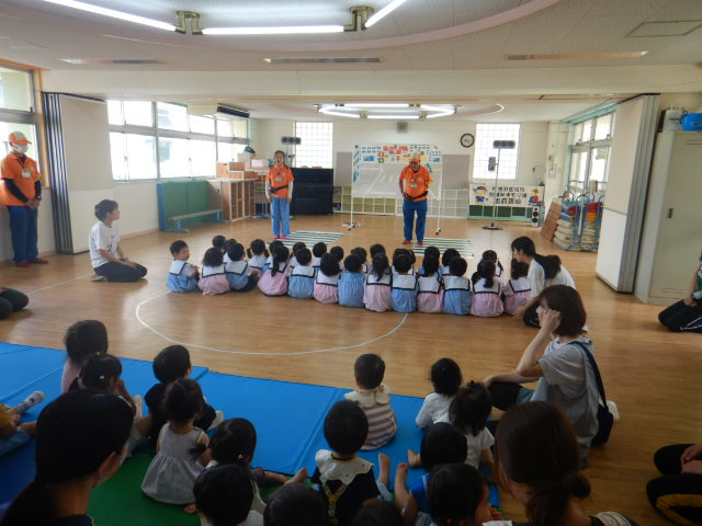 2・3歳児の前で自己紹介をする区役所職員と見学に来た1歳児