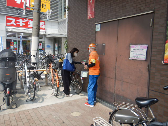 利用者に啓発物品を配付して注意喚起する区役所職員