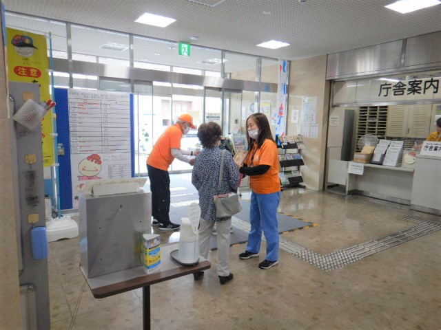 来庁者に啓発物品を配付し特殊詐欺に注意してと呼びかける区役所職員