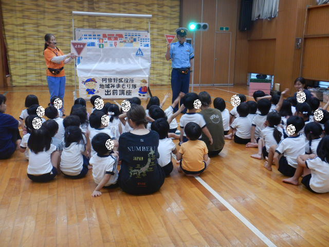 4・5歳児に止まれの標識を説明する警察官と区役所職員