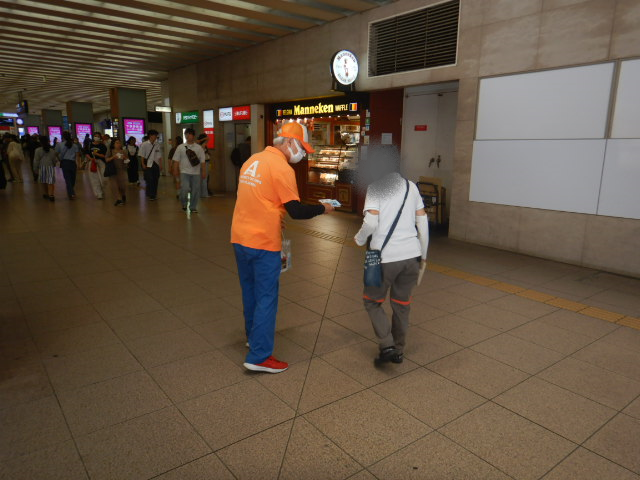 駅利用者に啓発物品を配付して注意喚起する区役所職員