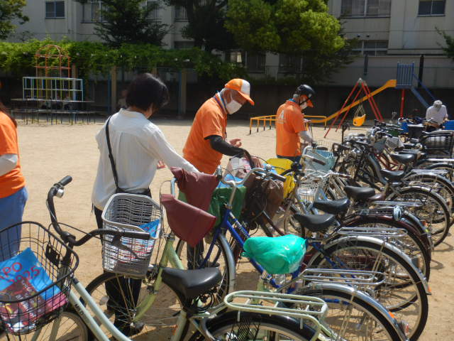 キャンペーン参加者の自転車前かごに啓発物品を配付する区役所職員