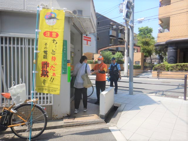 郵便局利用者に特殊詐欺被害防止を呼びかける区役所職員と警察官