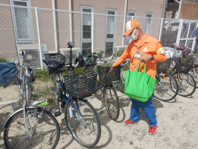 キャンペーン参加者の自転車前かごに啓発物品を配付する区役所職員