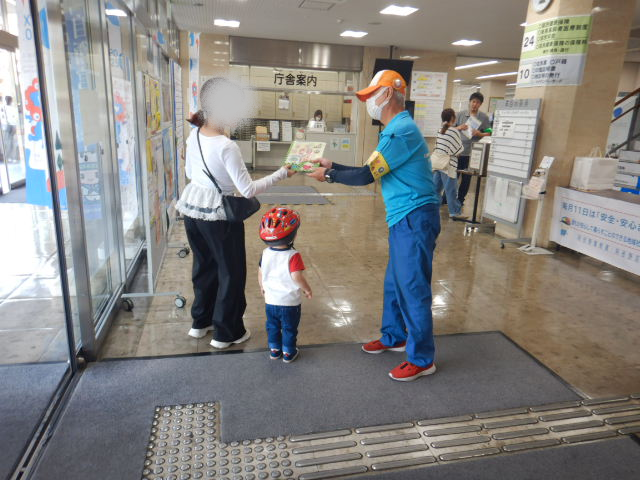 区役所玄関ロビーで来庁者に啓発物品を配付する区役所職員