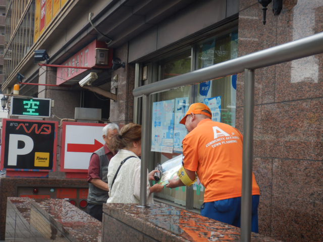 郵便局利用者に啓発物品を配付して注意喚起する区役所職員