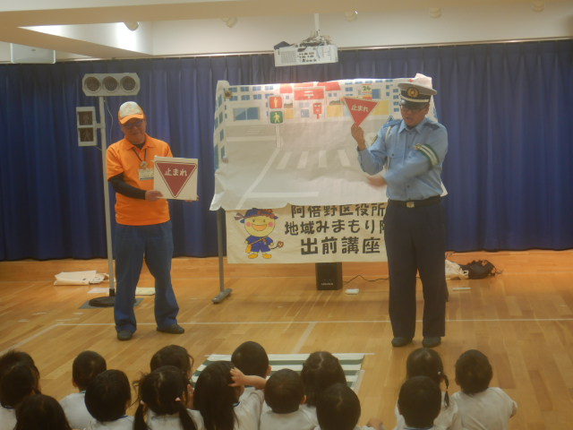 止まれの標識では必ず止まって右左右を確認するように園児に説明する警察官