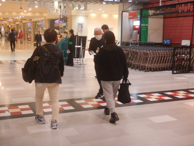 スーパー利用者に啓発物品を配付して注意喚起する区役所職員