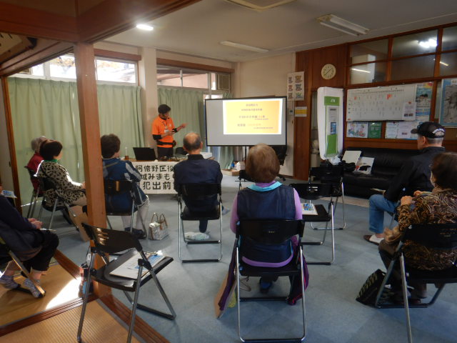 スクリーンにパソコン画像を映写し、参加者に詐欺の現状を説明する区役所職員