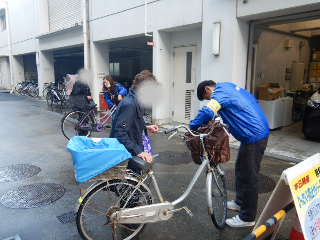 キャンペーン参加者にひったくり防止カバーを取りつける区役所職員