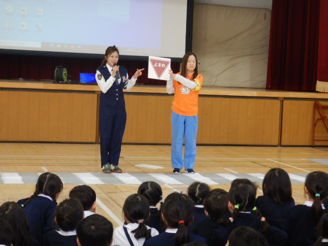 止まれの標識を見せ説明する警察官