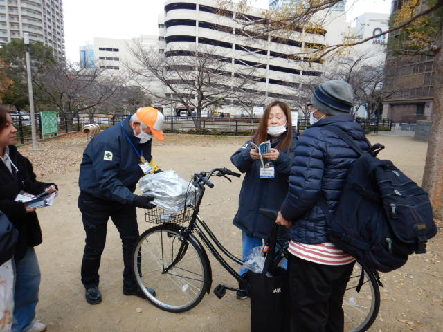 キャンペーン参加者の自転車にひったくり防止カバーを取りつけ、注意喚起する区役所職員