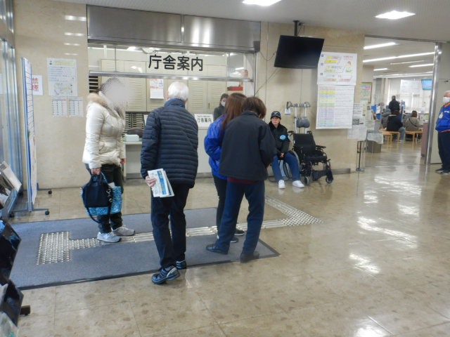 来庁者に啓発物品を配付して注意喚起する区役所職員