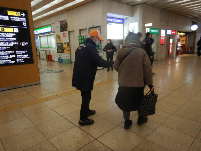 駅利用者に啓発物品を配付して注意喚起する区役所職員