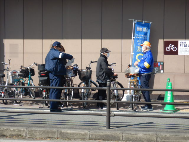 スーパー利用者に自転車の安全利用を呼びかける区役所職員と警察官