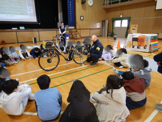 自転車を囲んで輪になり点検の仕方を学ぶ児童
