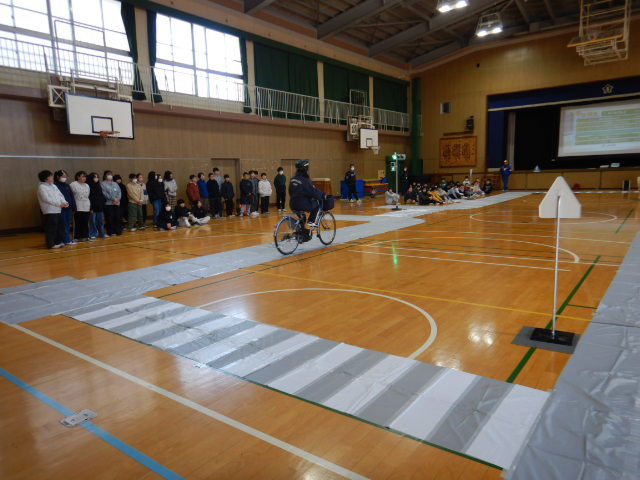 模擬道路で安全な自転車の走行を実演する区役所職員