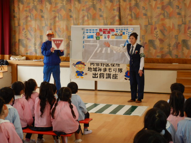 園児に止まれの標識の説明をする警察官