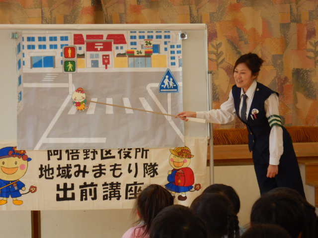 横断歩道の絵図を使って安全なわたり方を説明する警察官