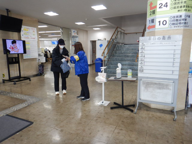 来庁者に啓発物品を配付して注意喚起する区役所職員