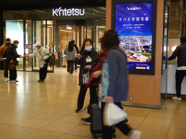 駅利用者に啓発物品を配付して注意喚起する区役所職員