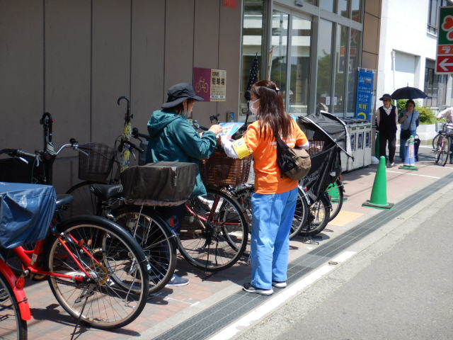 スーパー利用者に自転車の安全利用を呼びかける区役所職員