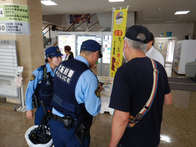 来庁者に特殊詐欺の仮想体験を説明する警察官