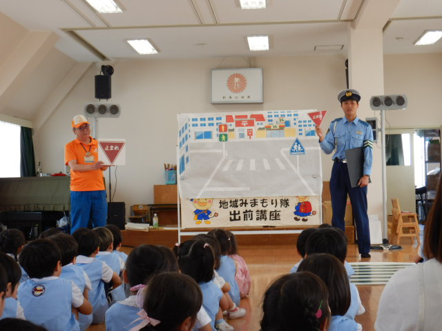 止まれの標識を見せて意味を説明する警察官