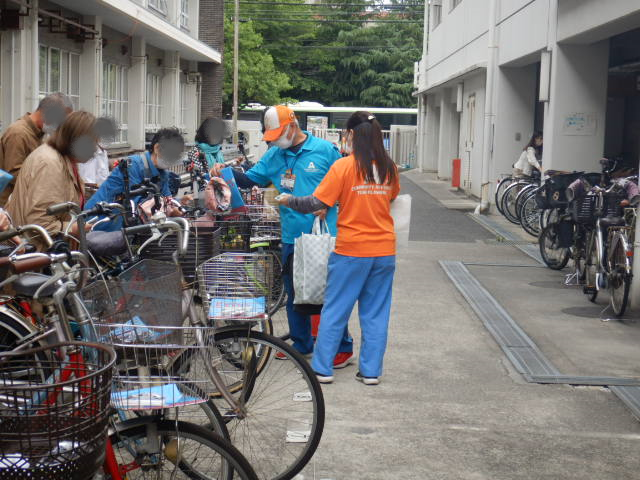 キャンペーン参加者の自転車前かごに啓発物品を配付する区役所職員