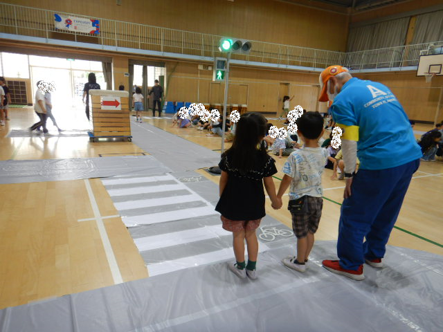 横断歩道の安全なわたり方を児童にアドバイスする区役所職員