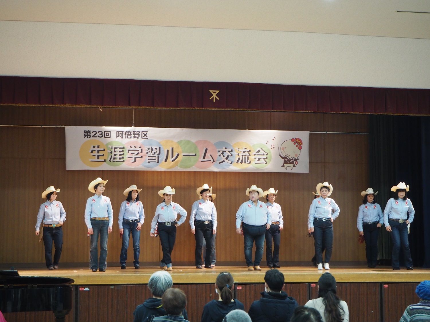 シャツの衣装をきたカントリーダンスのグループ10名が舞台上で踊っている様子