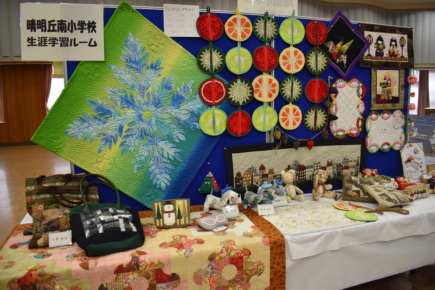 晴明丘南小学校生涯学習ルームのキルト作品がパネルと机に展示されている様子
