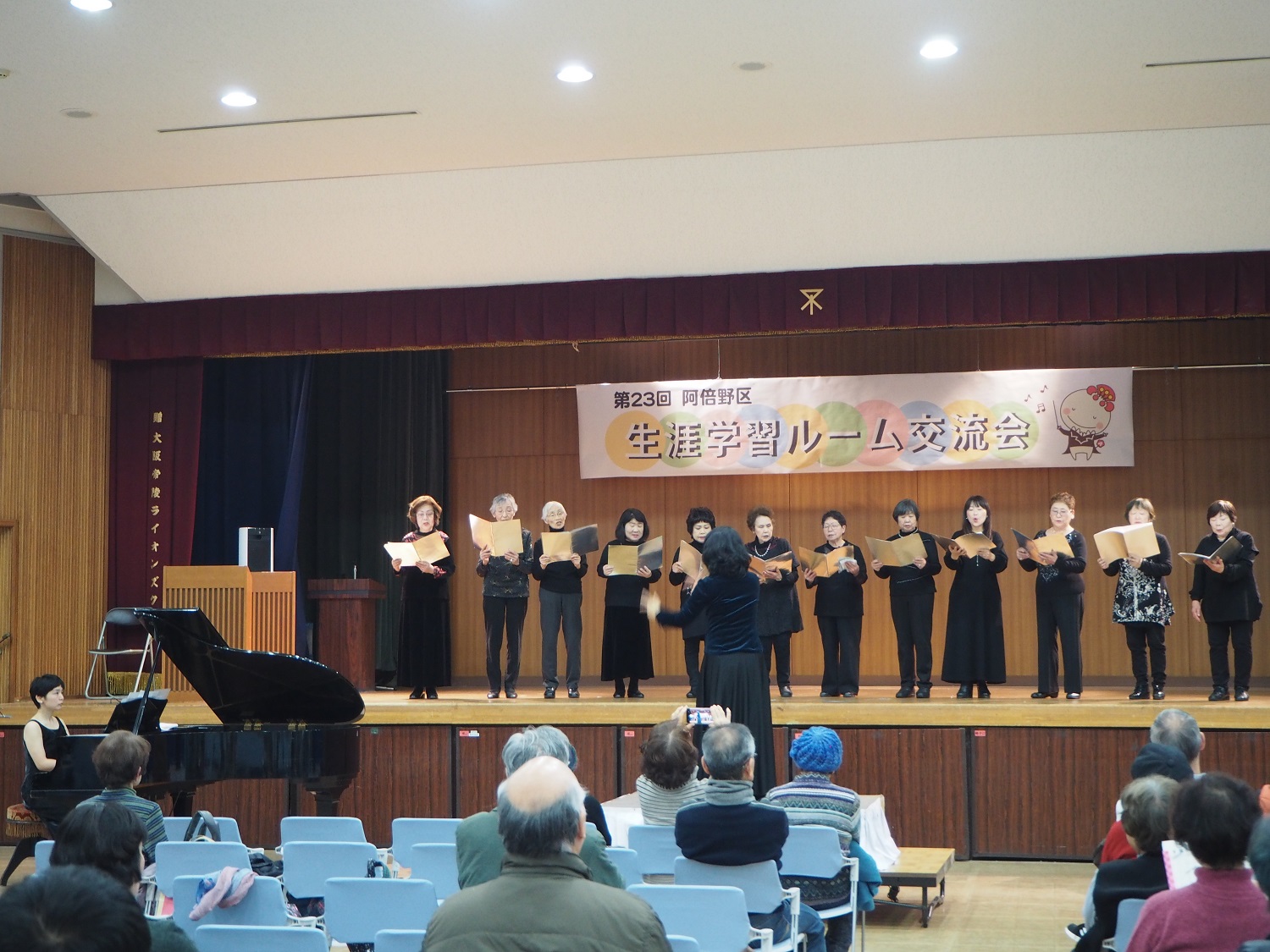 舞台上でコーラスグループの12名が歌っている様子