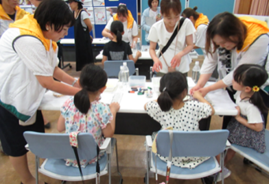 紙すきカードの作り方を教えてもらいながら作っている子ども