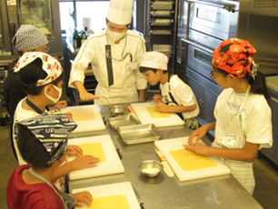 参加者がパスタ生地の作り方を学生から教わっている写真