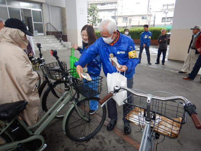 キャンペーン参加者の自転車前かごに啓発物品を配付する区役所職員