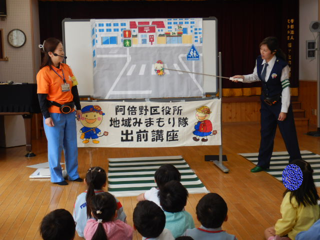 園児に横断歩道の安全な渡り方を絵図で説明する警察官
