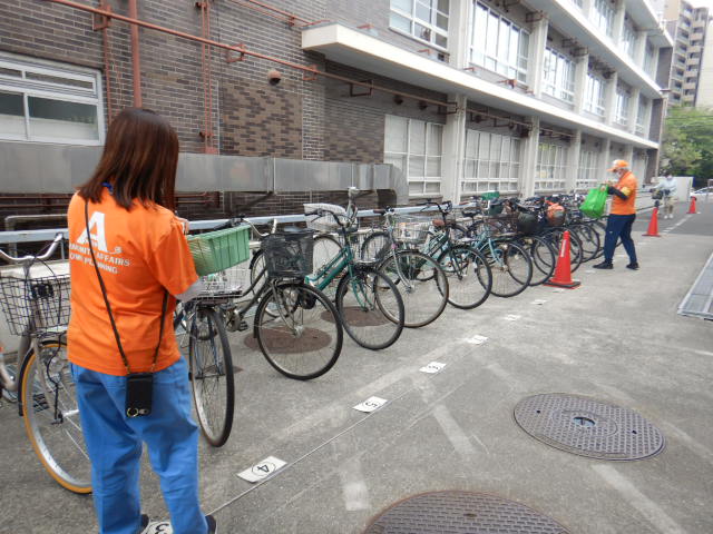 キャンペーン参加者の自転車前かごに啓発物品を配付する区役所職員