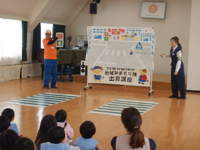 横断歩道の絵図を使って安全なわたり方を説明する警察官