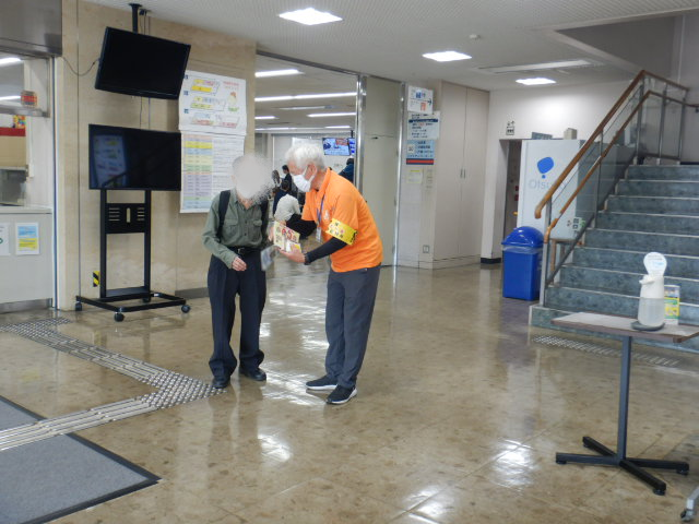 来庁者に啓発物品を配付して注意喚起する区役所職員