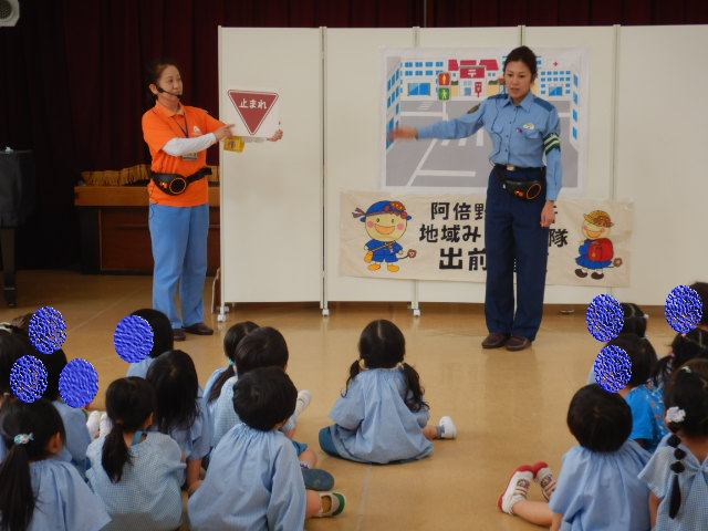 園児に止まれの標識を説明する警察官